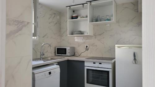 une cuisine avec un évier et un micro-ondes dans l'établissement Le Coin Zen du Vacancier, à Goussainville