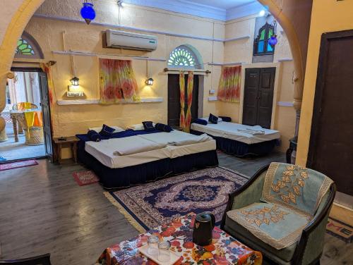 Zimmer mit 2 Betten, einem Stuhl und einem Tisch in der Unterkunft Sadar Haveli Heritage in Jodhpur