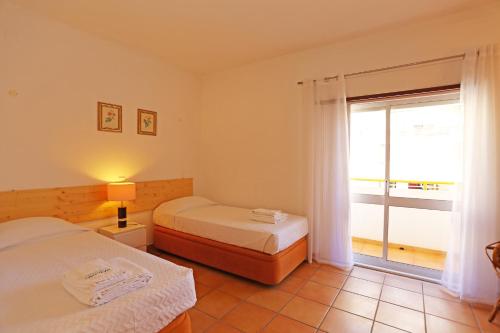 a bedroom with two beds and a large window at Casas do SOL GuestHouse Lagos in Lagos