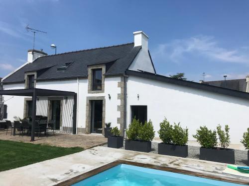 une maison blanche avec une piscine devant dans l'établissement Maison avec piscine 3 chambres, à Trégunc