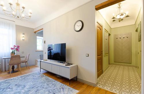 a living room with a television and a clock on the wall at Quiet garden deluxe apartment in Rīga