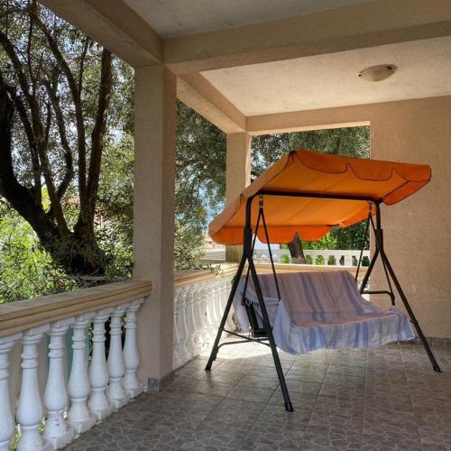 an orange umbrella on the porch of a house at Apartments Arina in Krasici