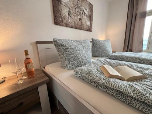 a bedroom with a bed with a book and a bottle of wine at Ferienwohnung Hansezauber in städtische Bestlage in Stralsund