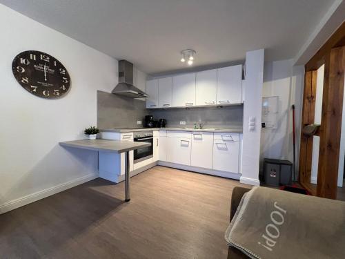 a kitchen with white cabinets and a clock on the wall at Ferienwohnung Hansezauber in städtische Bestlage in Stralsund