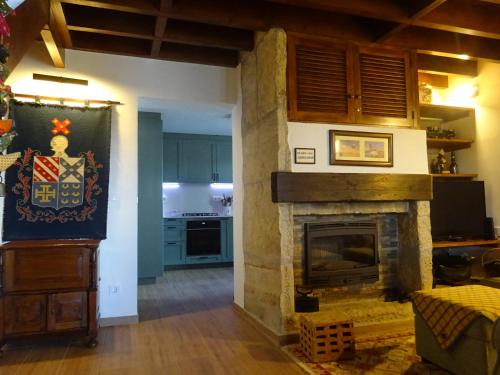 a living room with a fireplace and a kitchen at Casa dos Relvas in Godigana