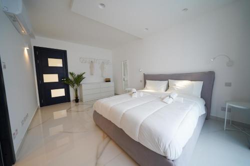 a large white bed in a white room with at Luxury brand new holiday apartments TOP location in Is-Swieqi