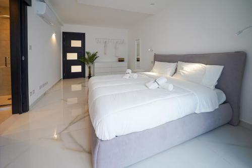 a bedroom with a large bed with white sheets at Luxury brand new holiday apartments TOP location in Is-Swieqi