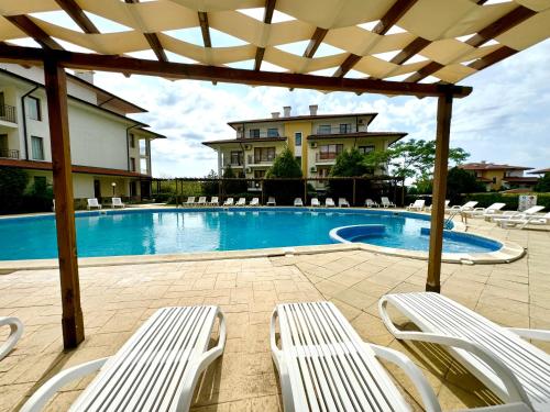 una piscina con sedie bianche e un pergolato di Arkite Complex a Sunny Beach