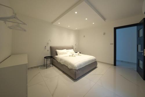 a white bedroom with a bed and a large window at Luxury brand new holiday apartments TOP location in Is-Swieqi