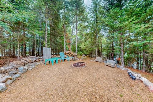 a picnic table and benches in the middle of a forest at Konkey's Kabin in Saint Germain