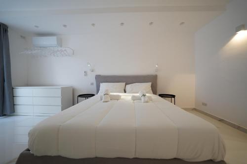 a white bedroom with a large white bed with two pillows at Luxury brand new holiday apartments TOP location in Is-Swieqi