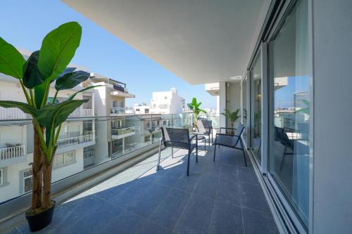 a balcony with two chairs and a plant on a building at Luxury brand new holiday apartments TOP location in Is-Swieqi