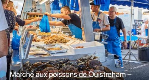 un groupe de personnes debout autour d'un marché de fruits de mer dans l'établissement Appartement à Ouistreham LA SIRENE, à Ouistreham