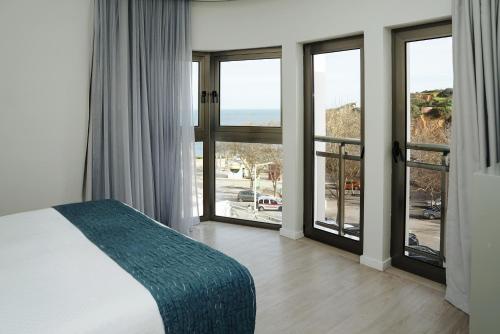 a bedroom with a bed and large glass windows at Carvi Beach Hotel in Lagos