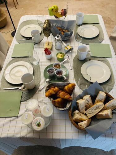 una mesa con platos de comida y pan. en La Cassiopée, en Caromb