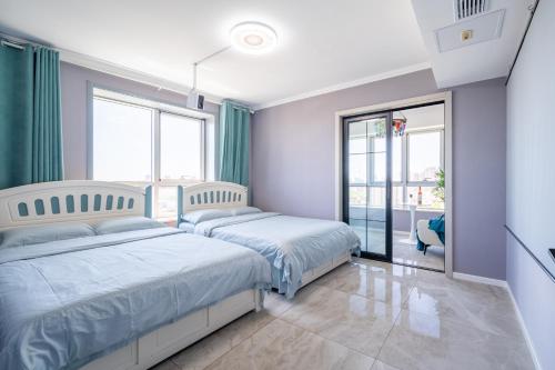 two beds in a bedroom with green curtains at Cloud & Sea Boutique Apartment in Rizhao