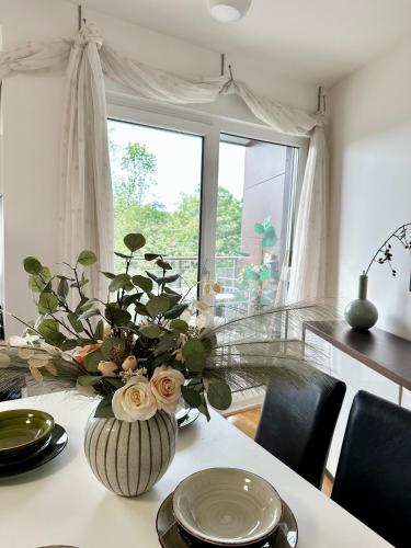 a dining room table with a vase of flowers on it at Prelep Pogled, Elegantan Komfor Blizu Centra, Besplatan Parking, Apartman Floresta in Vrnjačka Banja