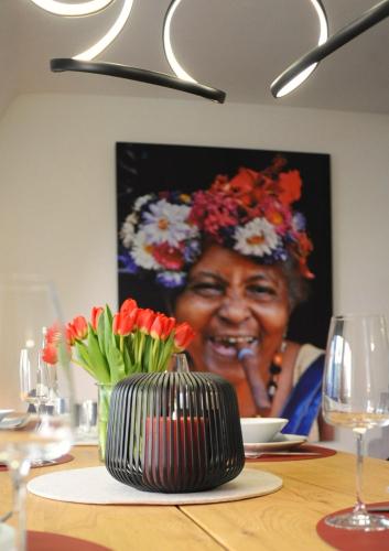 a woman sitting at a table with a vase of flowers at Deluxe-Apartment Altstadt in Ettlingen
