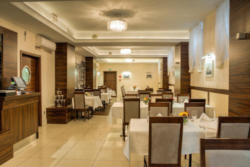 a restaurant with white tables and chairs and a dining room at Hotel Racibor in Racibórz