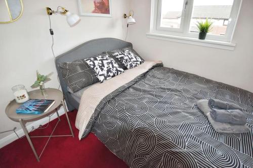 a bedroom with a bed and a table and a window at Modern house near Glasgow 3bdr in Dalmuir