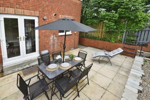 a table with chairs and an umbrella on a patio at Modern house near Glasgow 3bdr in Dalmuir