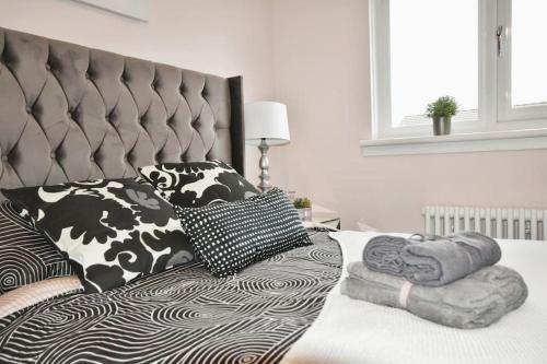 a bed with black and white pillows on it at Modern house near Glasgow 3bdr in Dalmuir