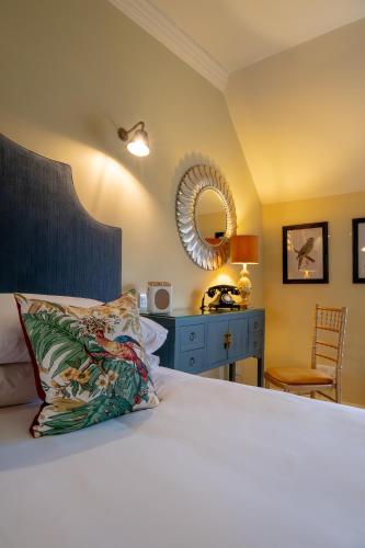 a bedroom with a bed and a mirror and a table at Leeds Castle Stable Courtyard Bed and Breakfast in Maidstone