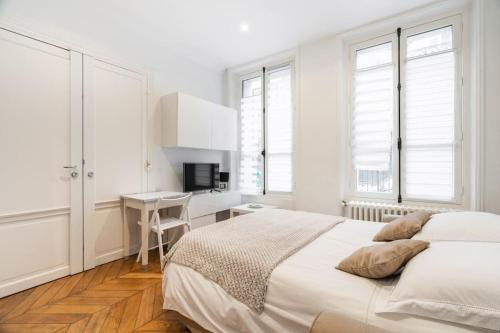 une chambre blanche avec un lit et un bureau dans l'établissement Studio Luxe Montaigne, à Paris