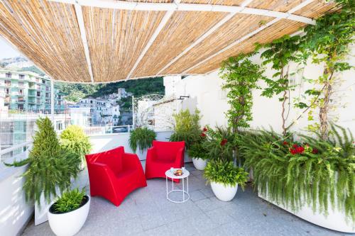 a balcony with red chairs and potted plants at Rooftop 19_Amalfi Luxury Suite in Amalfi