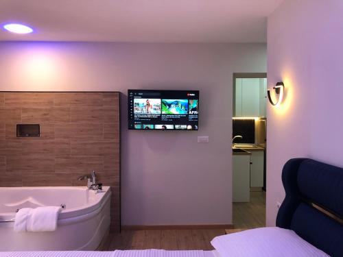 a bathroom with a tub and a tv on the wall at Deluxe Apartment In City Center in Tirana