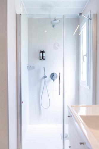 a white bathroom with a shower and a sink at Mangia's Pollina Resort in Cefalù