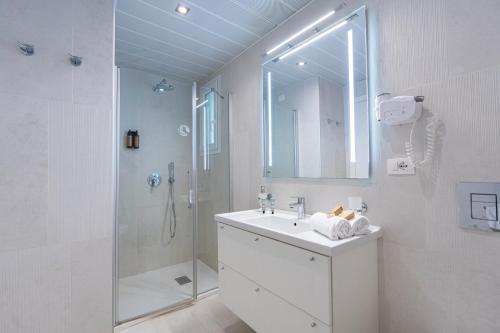 a white bathroom with a sink and a shower at Mangia's Pollina Resort in Cefalù