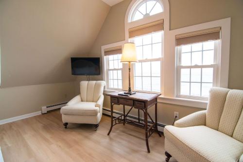 a living room with two chairs and a table and two windows at The Beach House Inn in Kennebunk