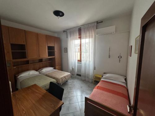 a bedroom with two beds and a table and a window at Casa Cloe in Rimini