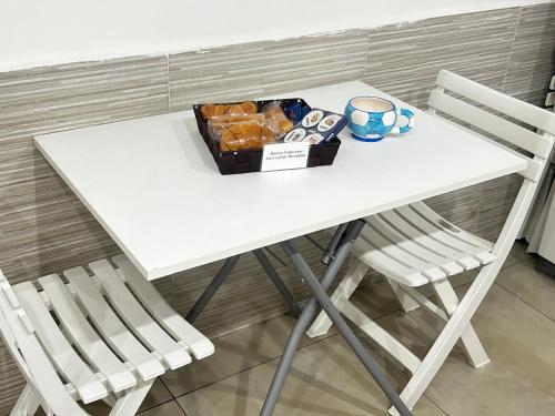 een witte tafel met twee stoelen en een doos gebak bij B&B Rifugio Partenopeo - Centro Storico di Napoli in Napels