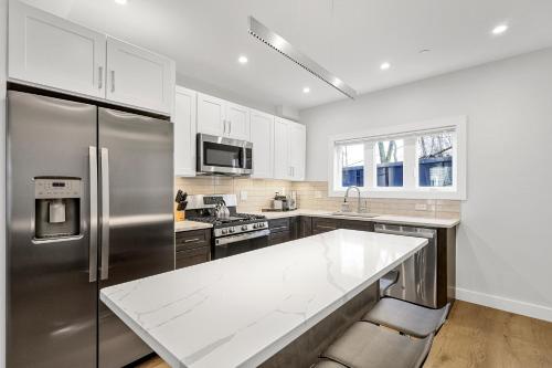 a kitchen with a stainless steel refrigerator and white cabinets at 3BR2Bth MIT Harvard TD Garden BOS 2 Parking Spaces in Somerville