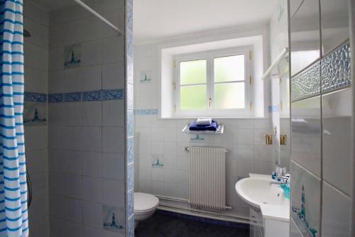a bathroom with a sink and a toilet and a window at Aggarthi Bed and Breakfast in Bayeux