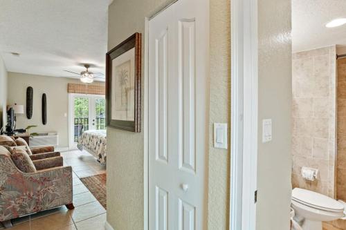 a bathroom with a toilet and a bedroom with a bed at Beso Del Sol Beauty Studio Oasis in Dunedin 409 in Dunedin