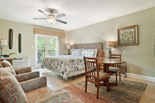 a bedroom with a bed and a table and a couch at Beso Del Sol Beauty Studio Oasis in Dunedin 409 in Dunedin