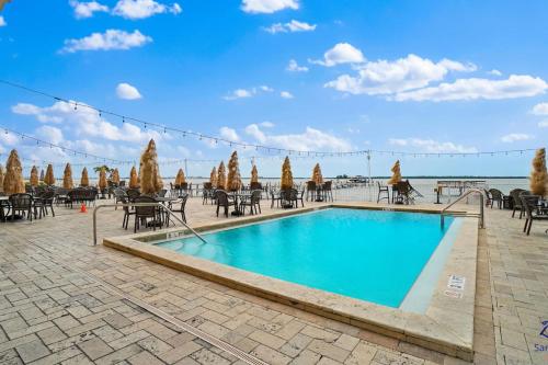 a swimming pool with tables and chairs in a resort at Beso Del Sol Beauty Studio Oasis in Dunedin 409 in Dunedin