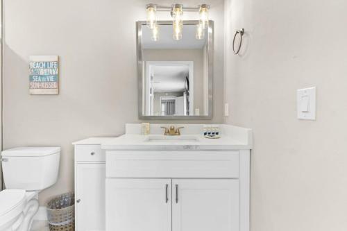 a white bathroom with a sink and a mirror at Private Seminole Pool Home Just minutes to the beach in Cross Bayou