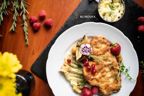 a white plate with a piece of chicken and strawberries at Hotel Diamond w Białym Dworku in Rumia