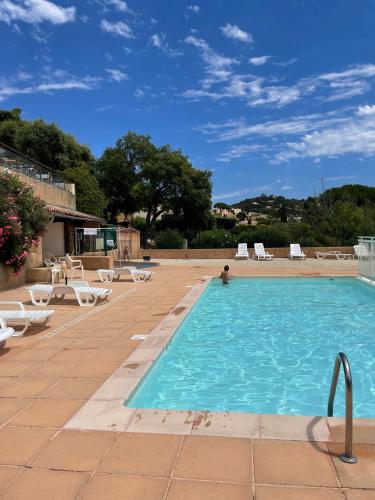 une grande piscine avec des chaises et une personne dans l'eau dans l'établissement Studio Bruno, vue mer, avec piscine, Golfe de Saint Tropez, à La Croix-Valmer