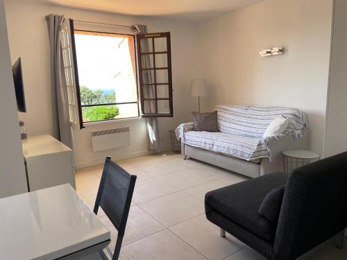 un salon avec un canapé et une fenêtre dans l'établissement Studio Bruno, vue mer, avec piscine, Golfe de Saint Tropez, à La Croix-Valmer
