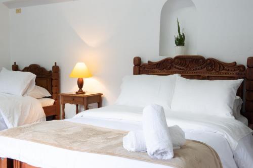 a bedroom with two beds with white sheets and towels at Hotel Beth Sarim in Villa de Leyva