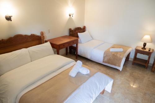 a hotel room with two beds and a desk and a table at Hotel Beth Sarim in Villa de Leyva