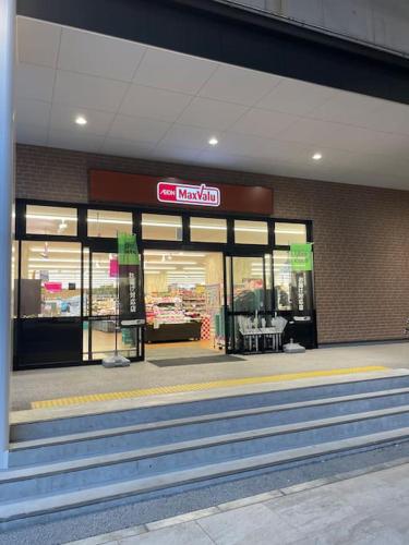a store front of a grocery store with a sign on it at ゲストハウスEn 折尾駅前邸 in Orio