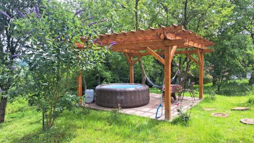 a wooden pergola with a hot tub in a garden at Kokotova hiža in Gornja Konjšćina