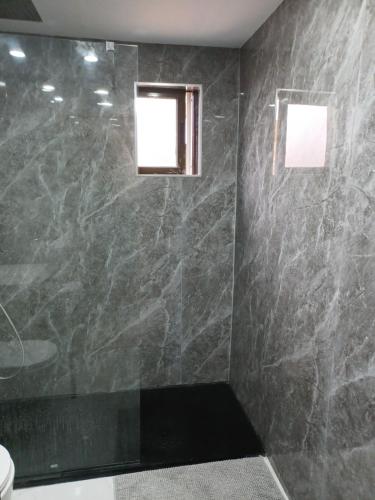 a bathroom with a shower with a black marble wall at Oporto Cozy Rooms in Porto
