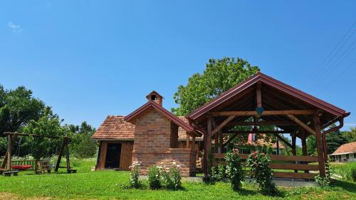 a wooden pavilion in a grassy field next to a park at Kokotova hiža in Gornja Konjšćina